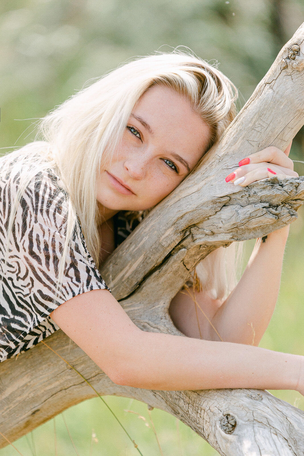 blond girl laying on tree branch