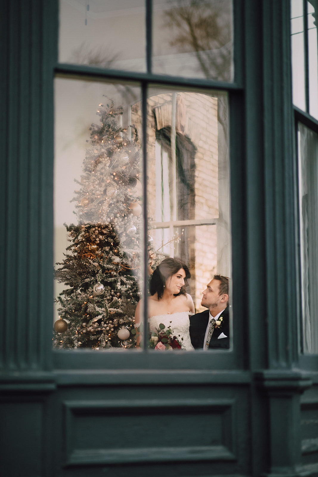 Bride and groom photographed through a window at the Covenant at Murray Mansion