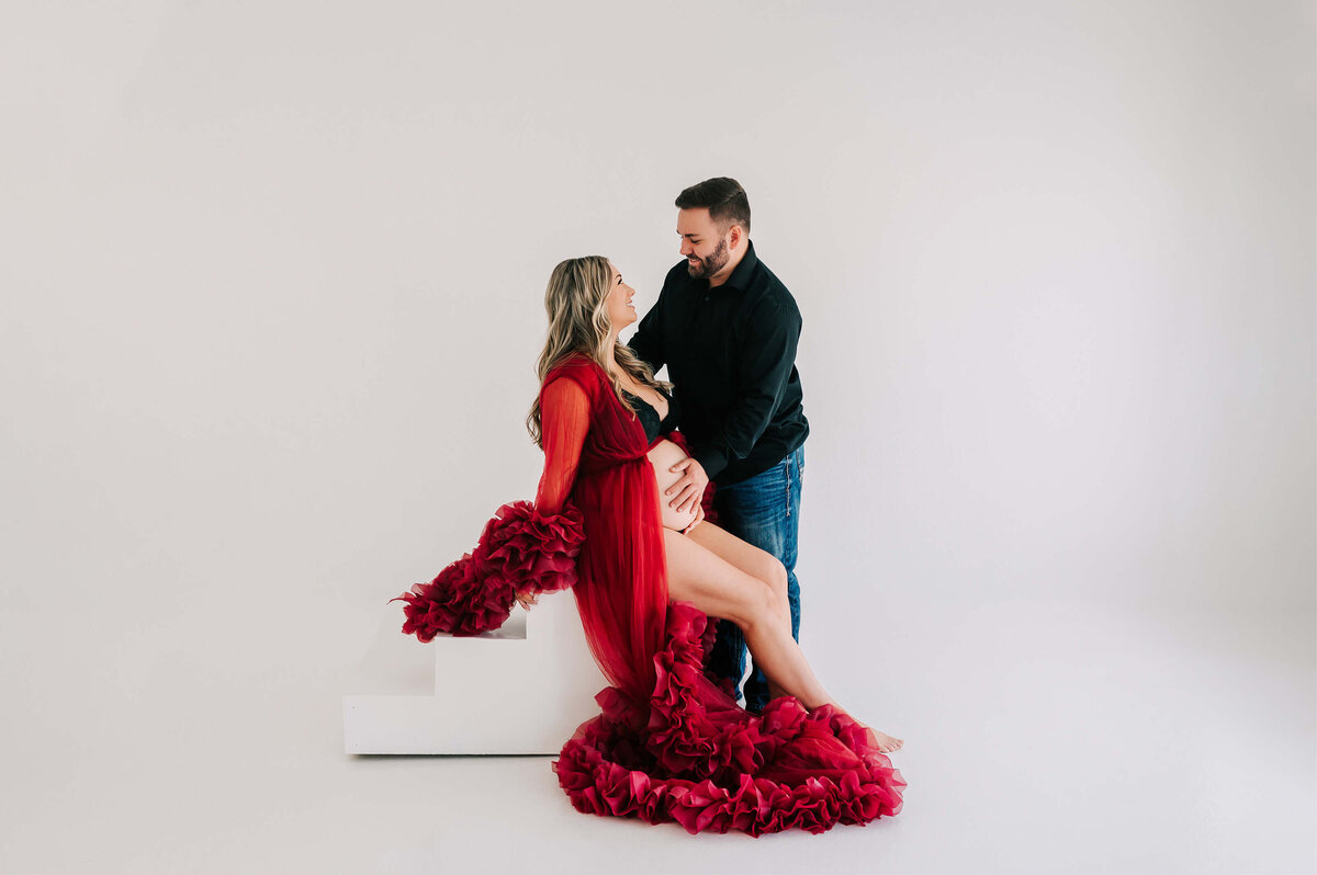maternity photo of pregnant couple looking at each other in studio