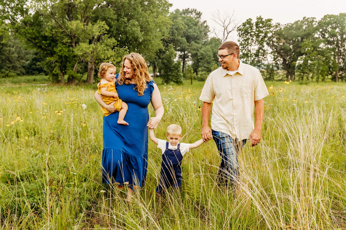 beautiful family with two toddlers walking and laughing in a field near Oshkosh