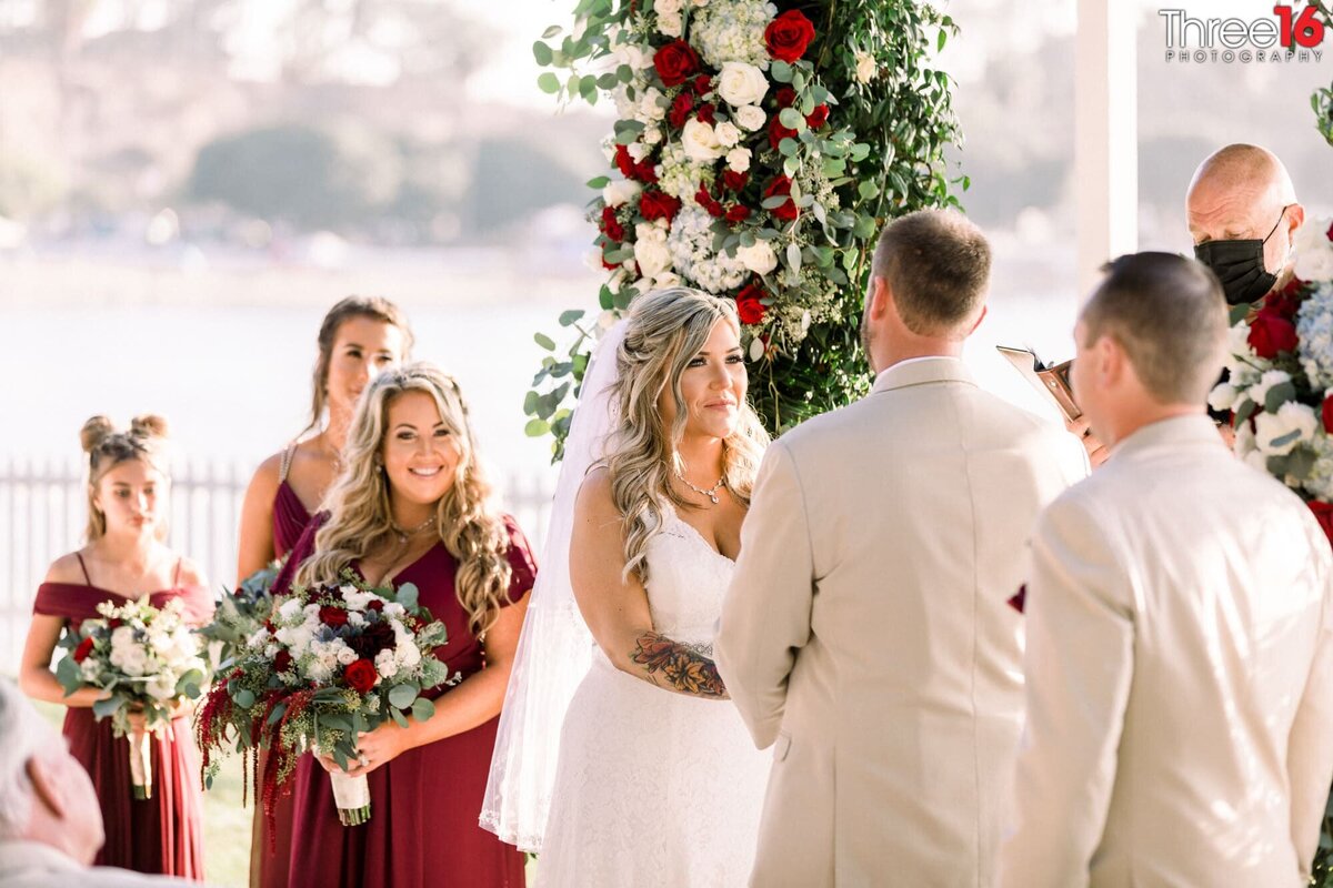 Bride looks at her Groom while holding hands as the bridesmaids look on