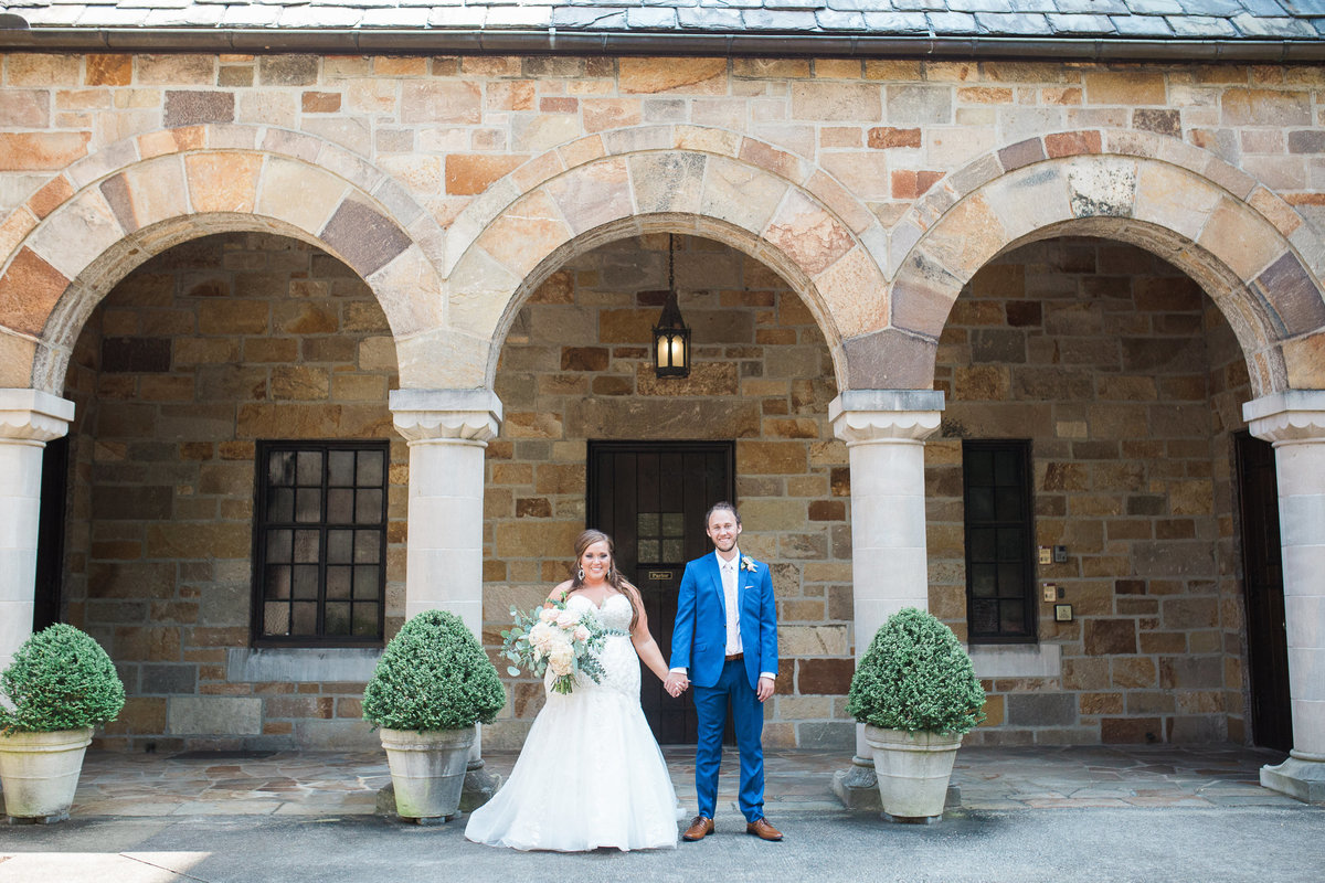 Wedding Photographer, bride and groom standing in front building columns