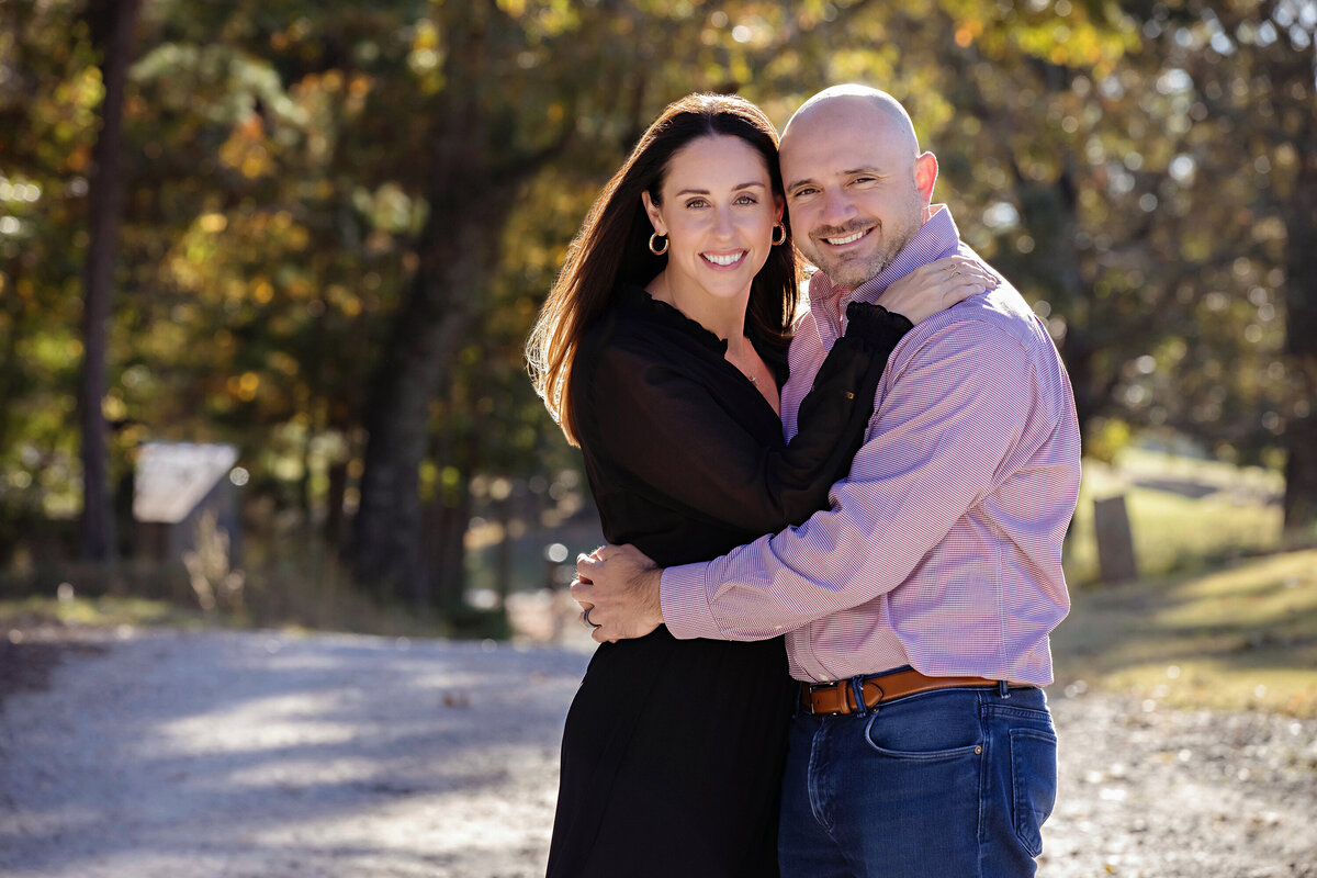 Stylish parents posing on tree‑lined gravel road in autumn at Anne Springs Close Greenway Charlotte NC