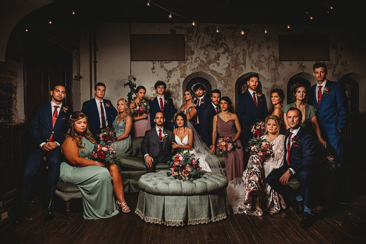 Bridal party photo with bride and groom sitting on a large couch together surrounded by the bridal party in an elegant lounge for their Baltimore wedding with Baltimore wedding photographers