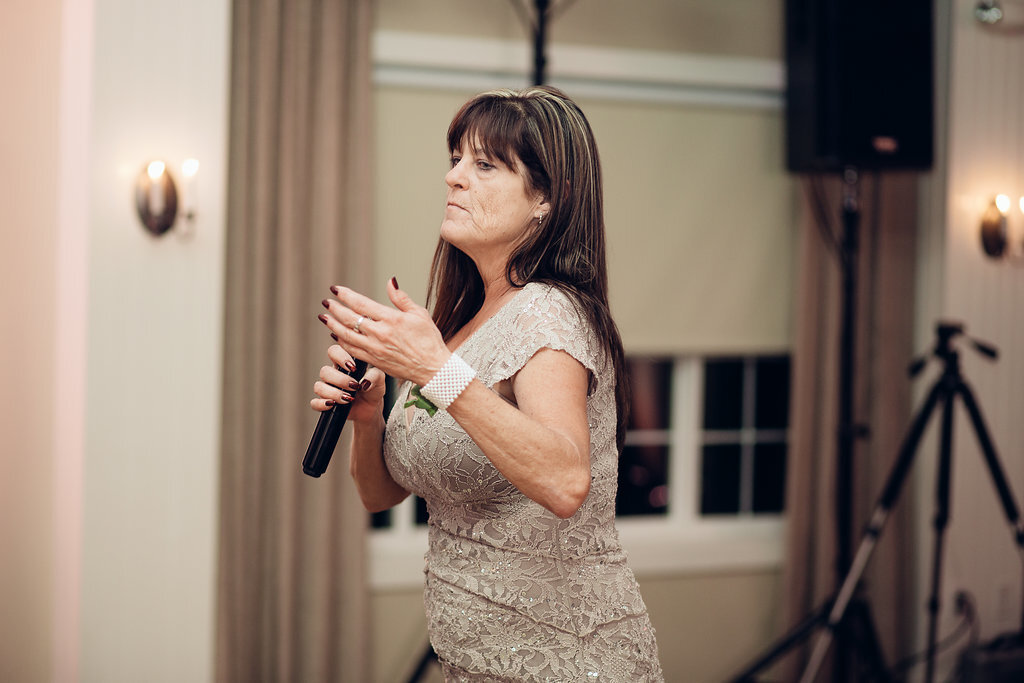 Wedding Photograph Of Woman In Light Brown Dress Raising Her Hand While Holding a Microphone Los Angeles