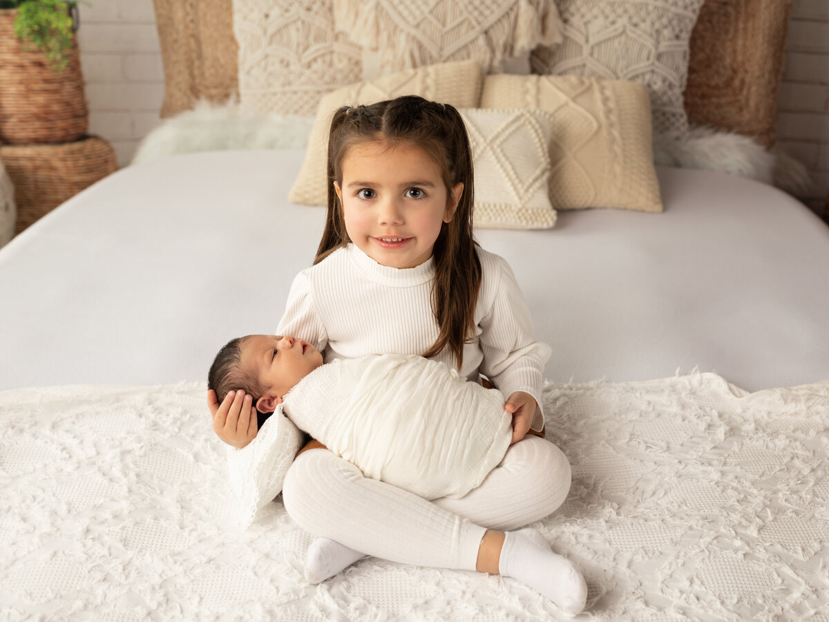 big sister holding newborn brother for photoshoot
