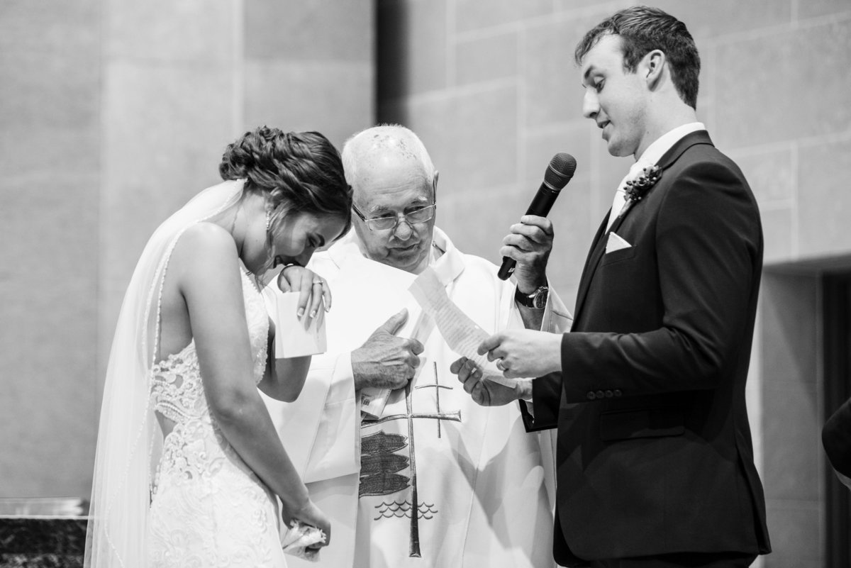 Bride laughs during vows at church wedding.