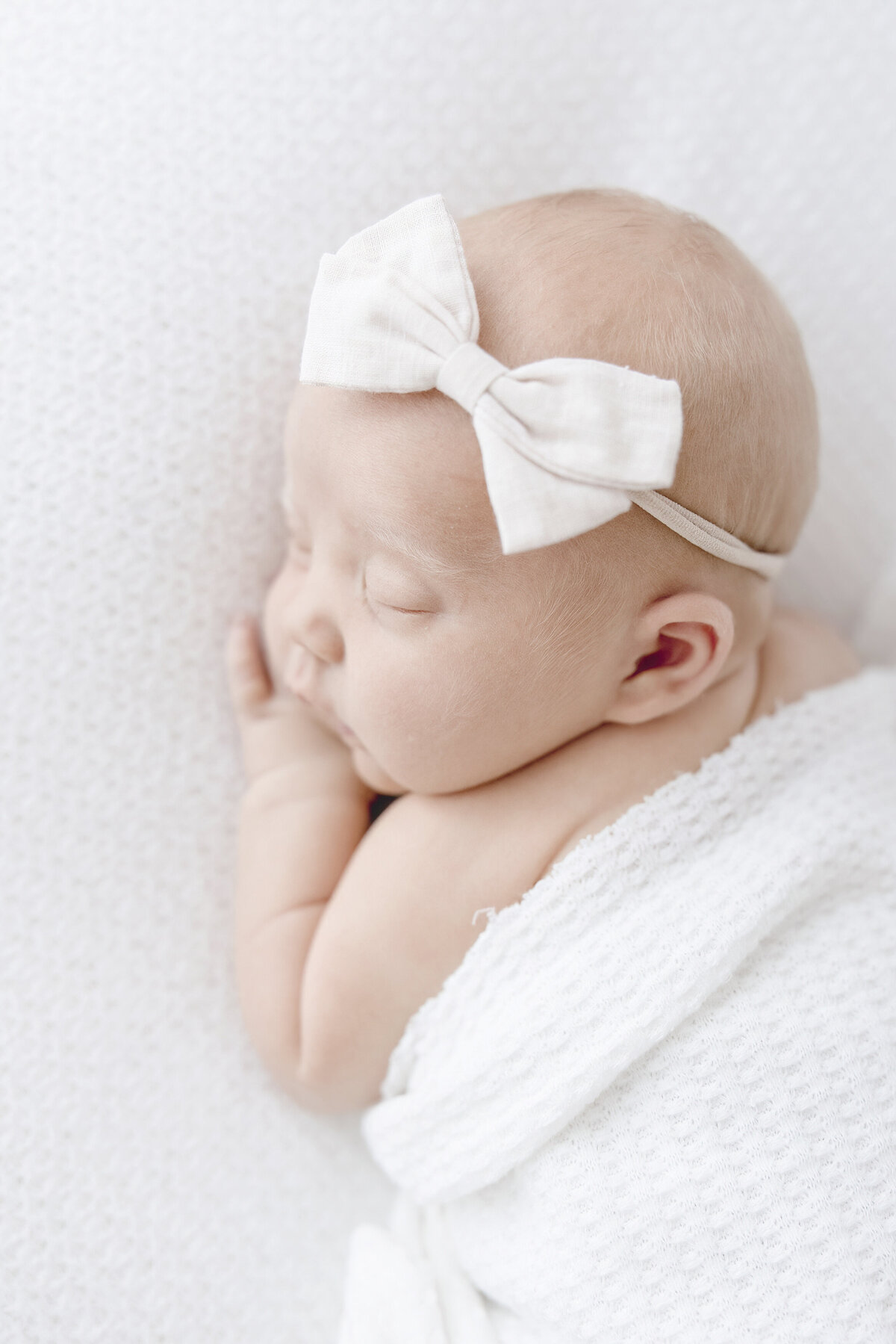 Newborn baby with white wrap and bow