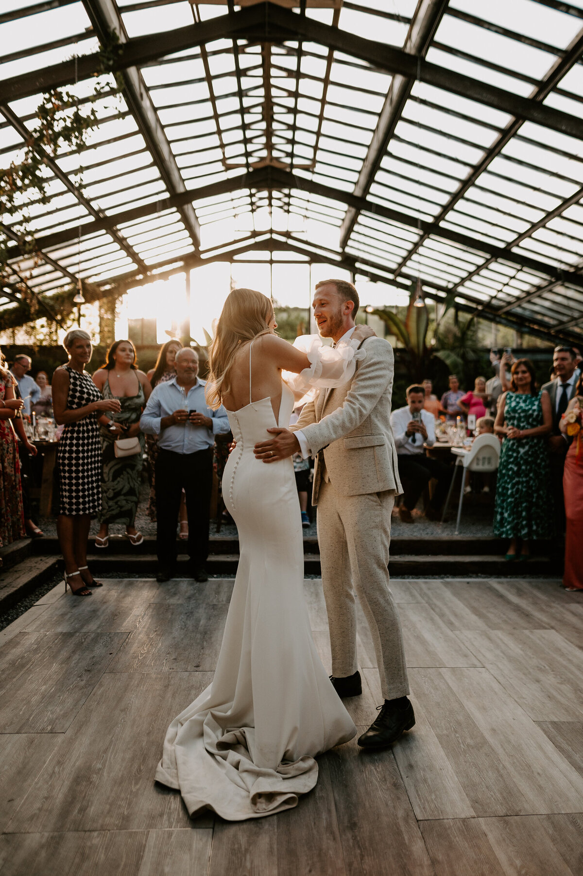 A sunset comes through the glasshouse at ANRAN whilst a bride and groom share their first dance.