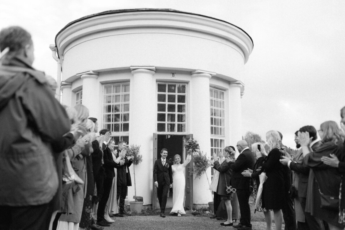 A documentary wedding  photo of the wedding couple leaving the wedding ceremony in the orangerie in Oitbacka gård captured by wedding photographer Hannika Gabrielsson in Finland