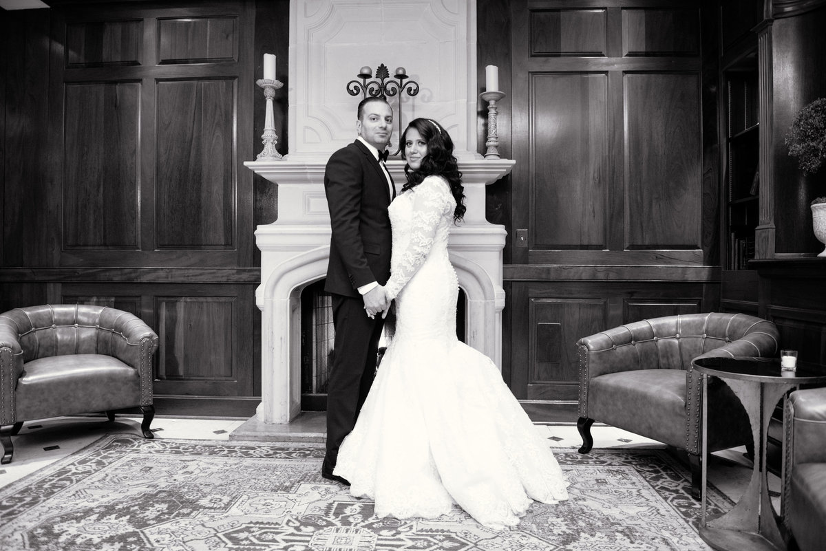 Bride and groom by fireplace in black and white at The Somerley