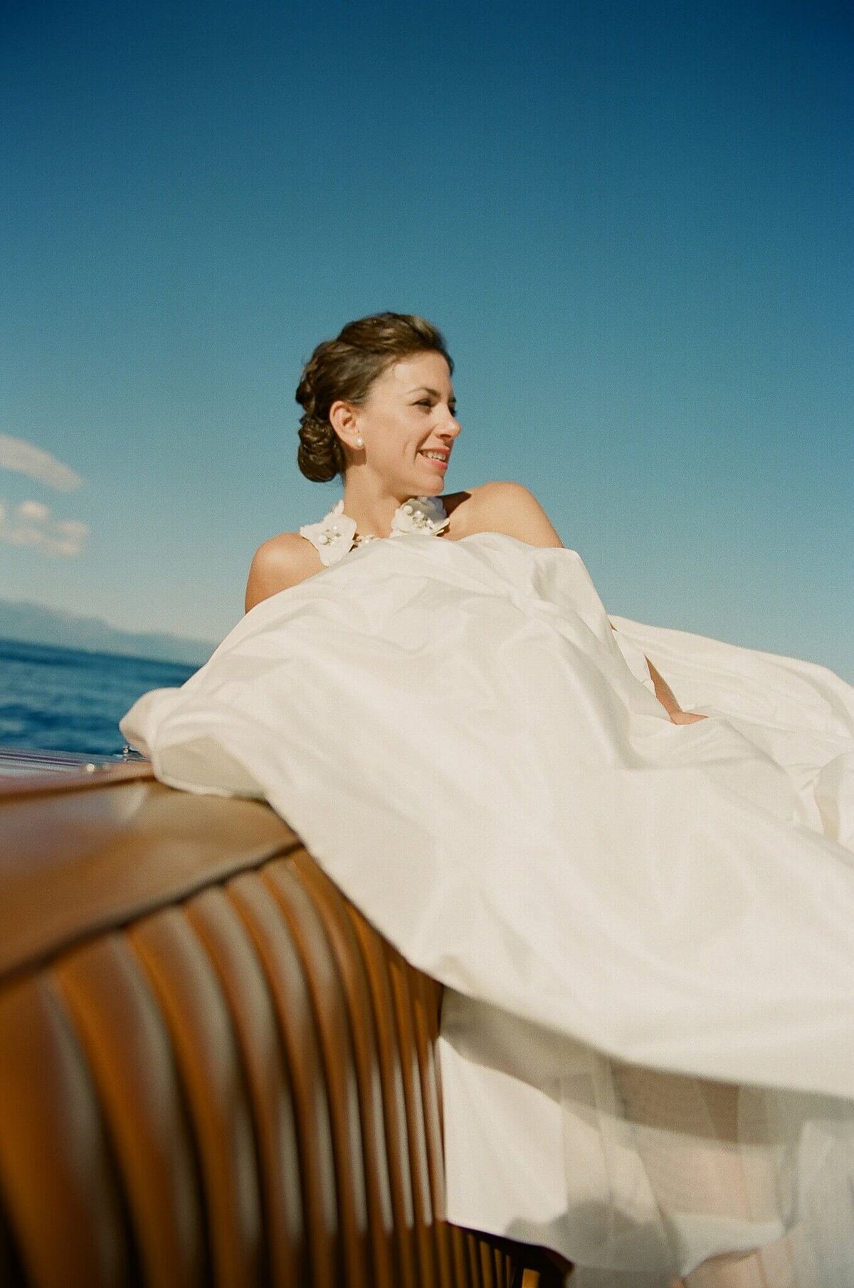 Film image of bride sitting in vintage boat on Lake Tahoe