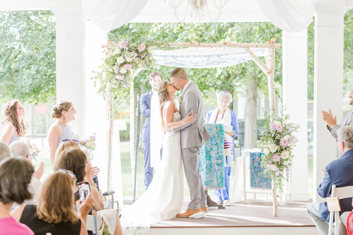 Bride and Groom share their first kiss at their Five Bridge Inn wedding ceremony. Captured by best Massachusetts wedding photographer Lia Rose Weddings.