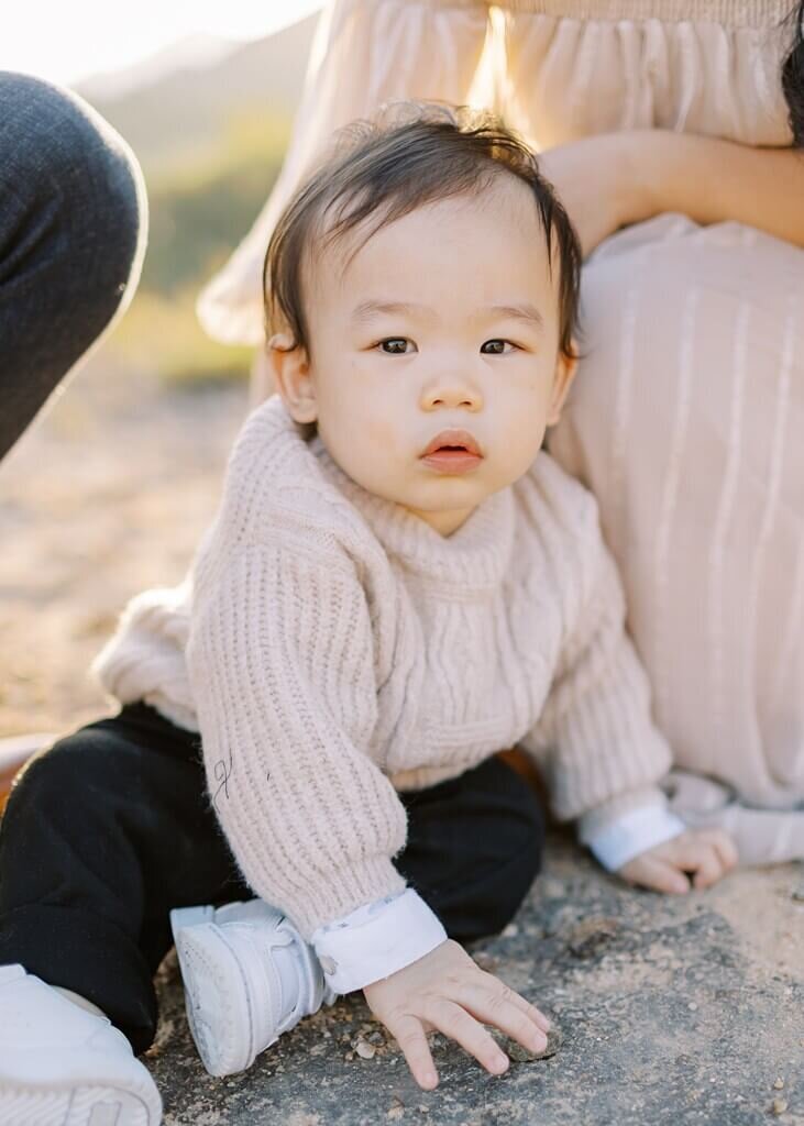 Close up shot of young child sitting on the ground looking at the camera.