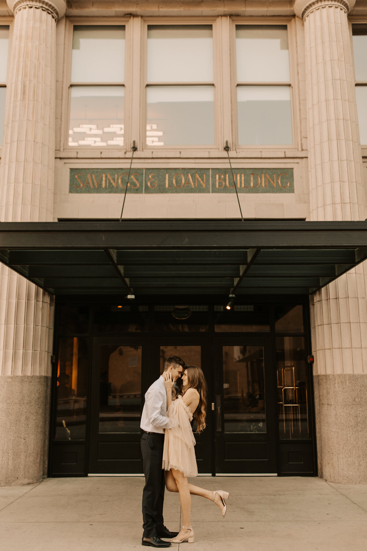 elegant engagement photos in front of a hotel in downtown des moines, Iowa