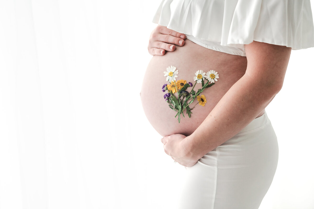 A blossoming future: expectant mother cradling her belly adorned with delicate flowers, symbolizing new life and natural beauty.