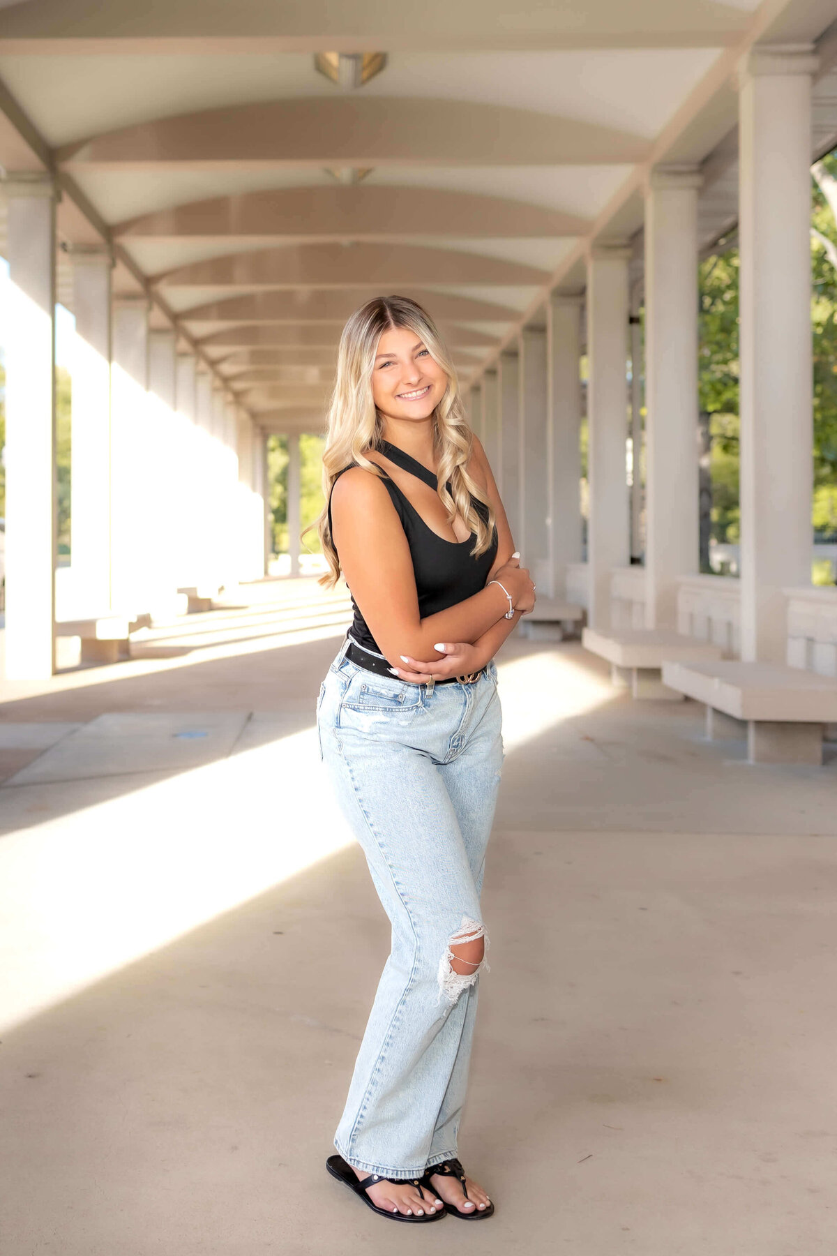 blonde haired high school senior  girl standing in a covered walkway