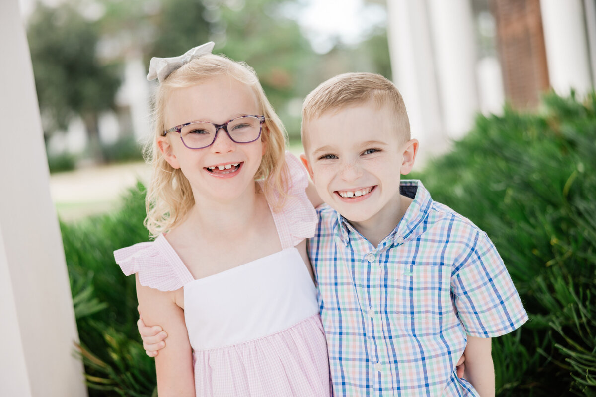 Two siblings smiling with their arms around each other