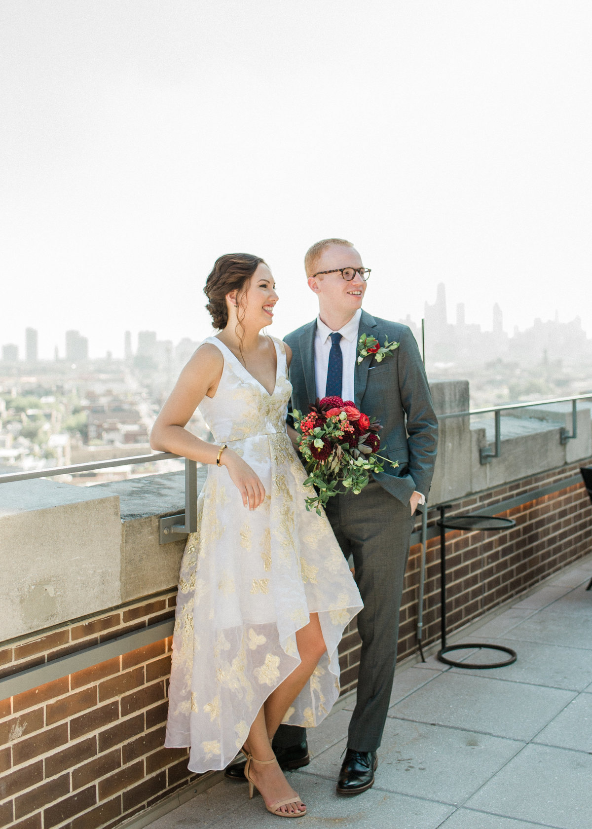 couple smiling on rooftop with skyline in background