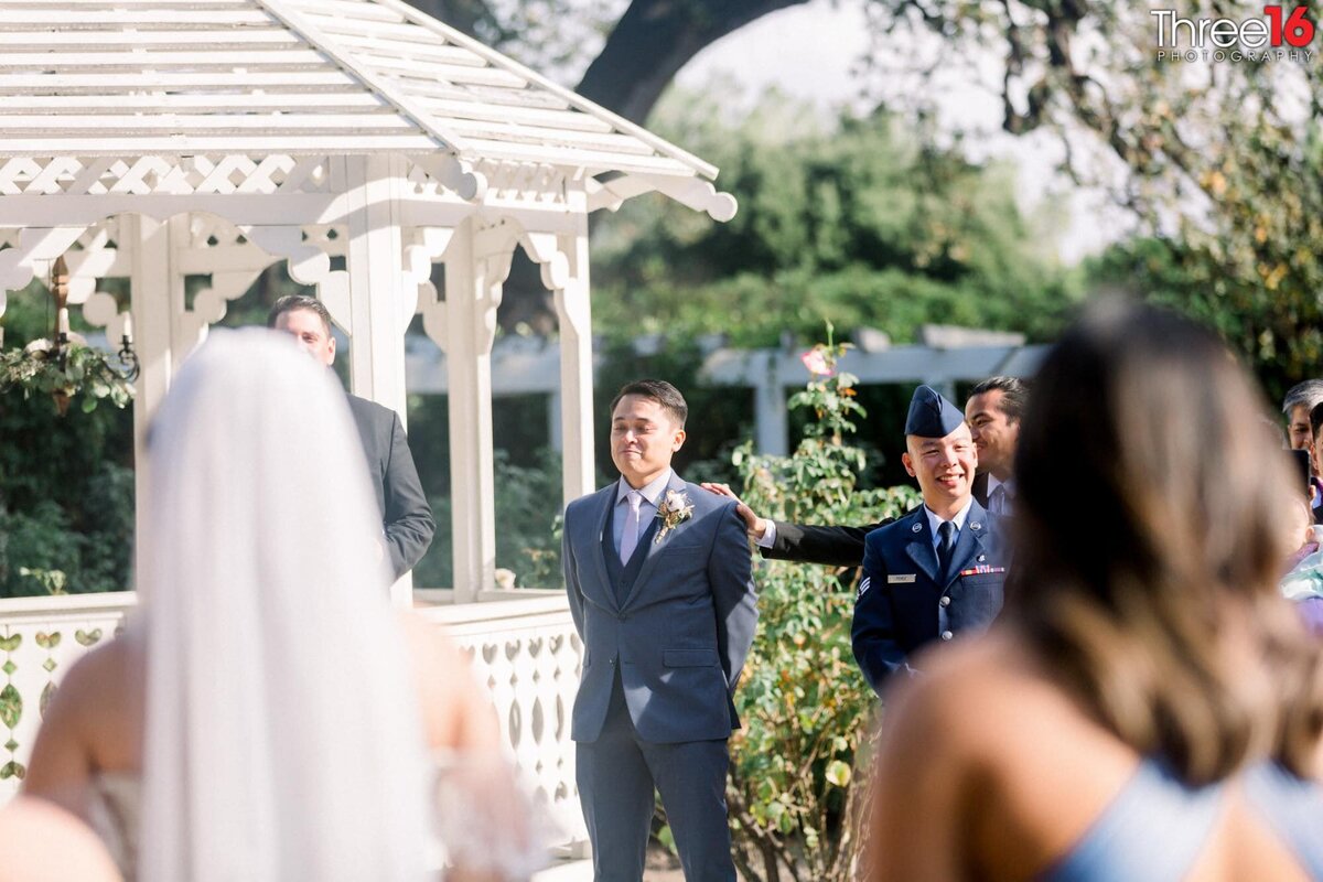 Groom tries not to cry as he stands at the altar watching his Bride walk up the aisle