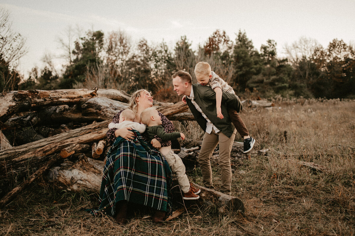 family of five cuddling on fallen logs