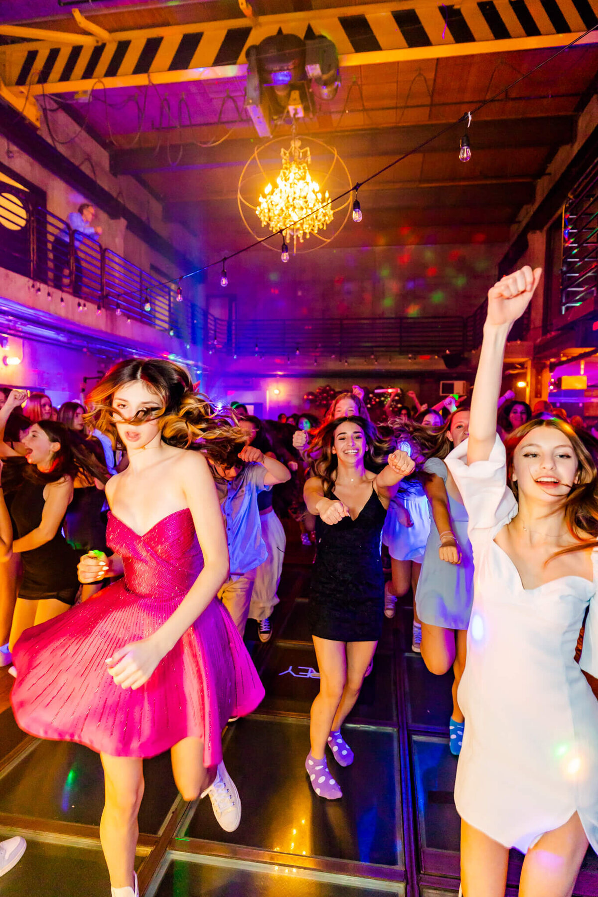A group of teen girls dance on the dance floor in pink and white dresses