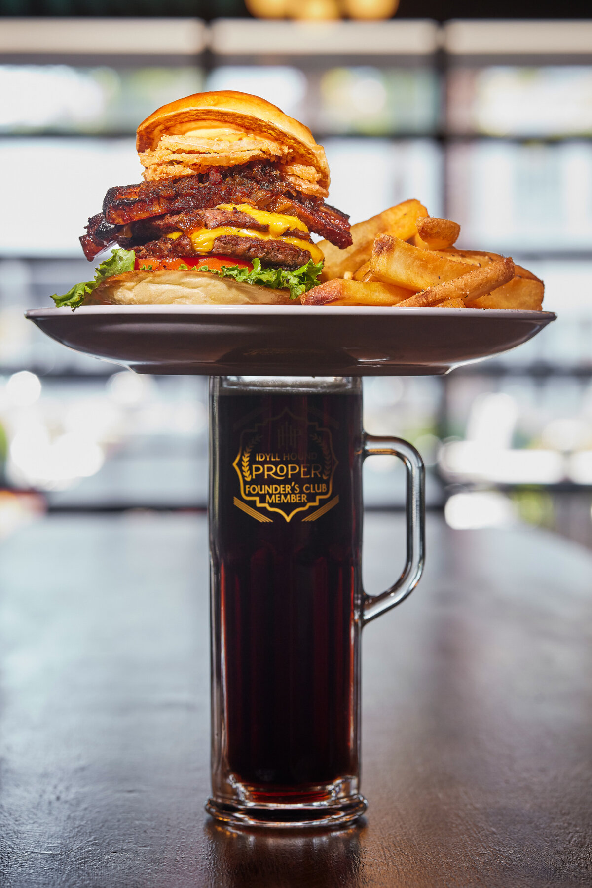 A burger and fries on top of a pint of beer