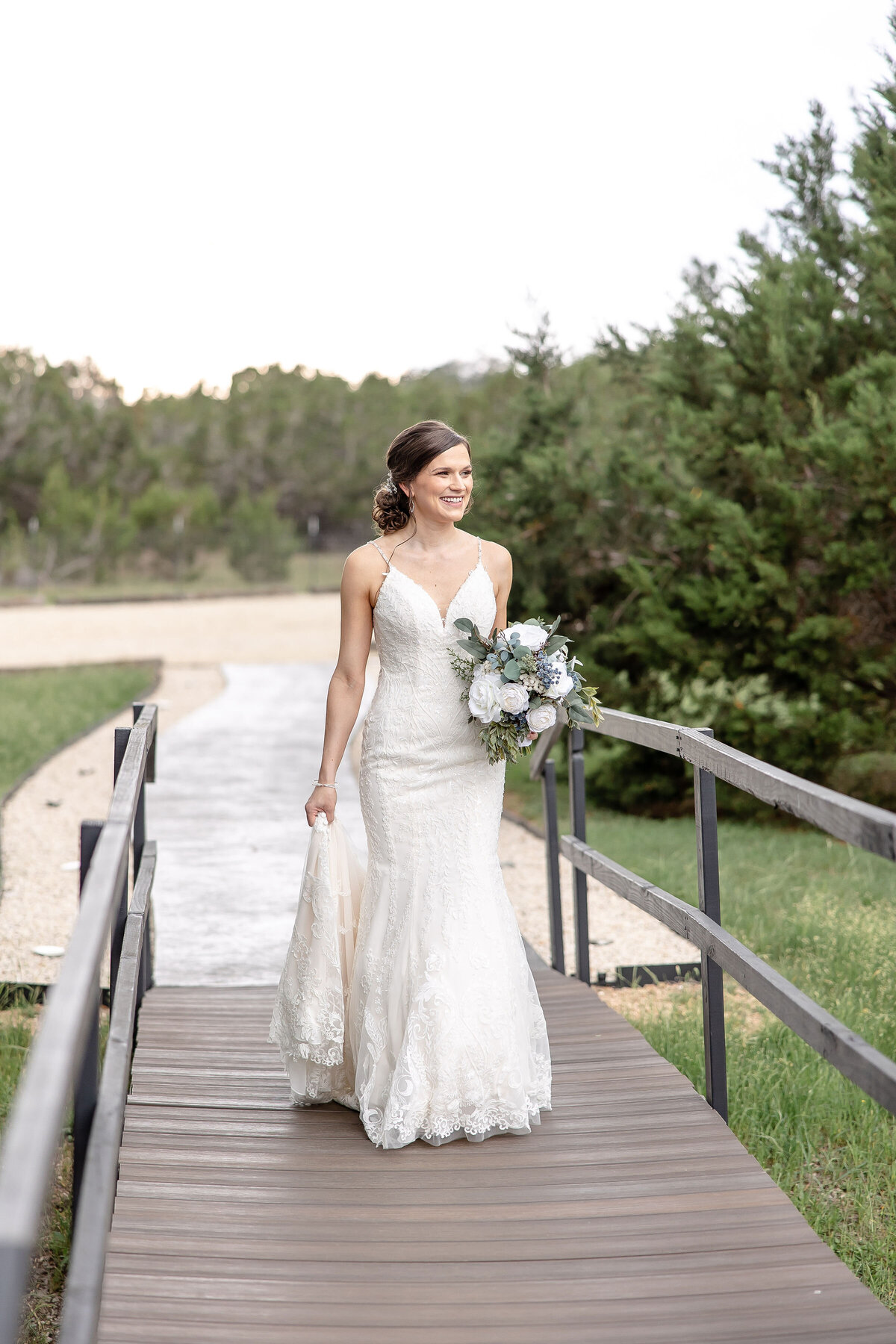 wedding photographer captures bride walking along bridge at Morgan Creek Barn in Dripping Springs Texas