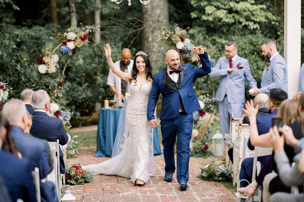 Bride & groom wave at family as they walk down aisle. The Wheeler House Photographer