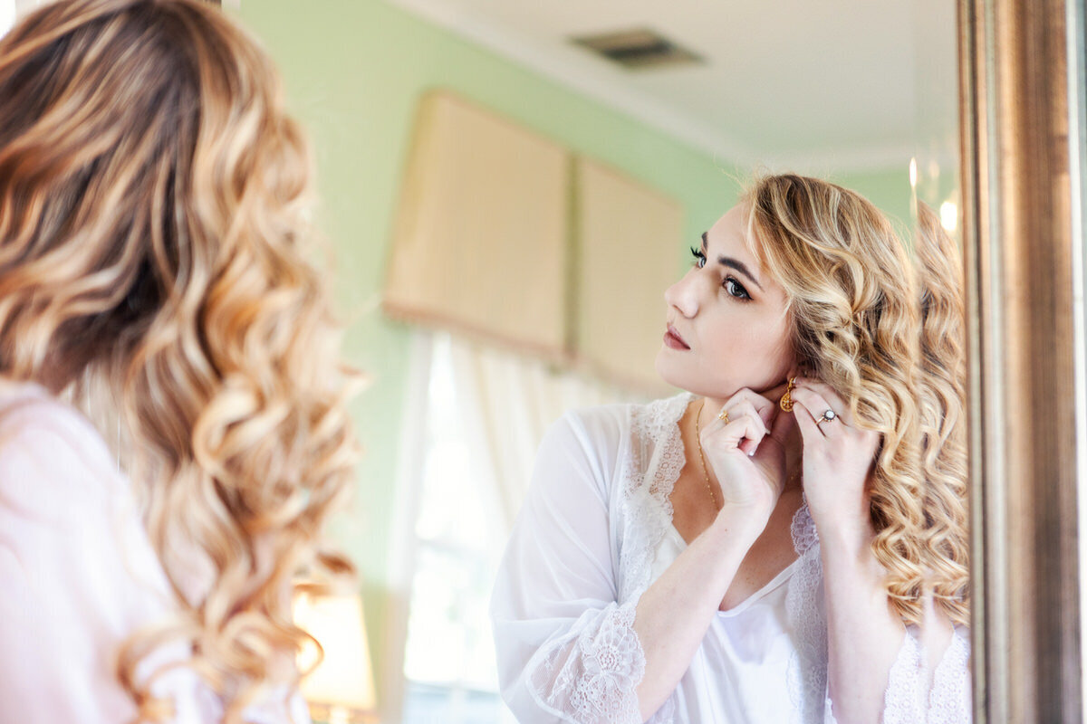 Bride putting on earrings at Legare Waring House Charleston Wedding Photographer