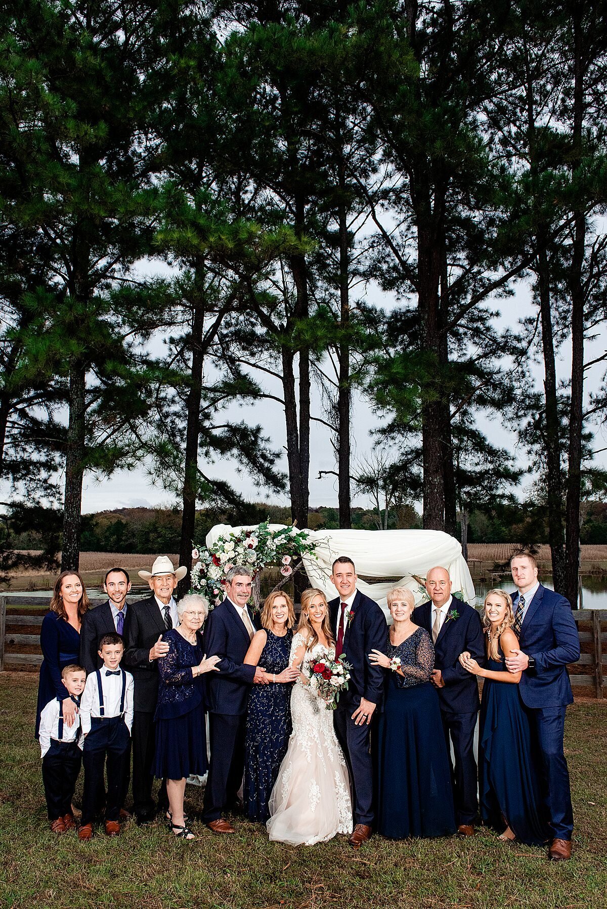 Formal photo of both sides of the family all together with the newlyweds in front of the arbor