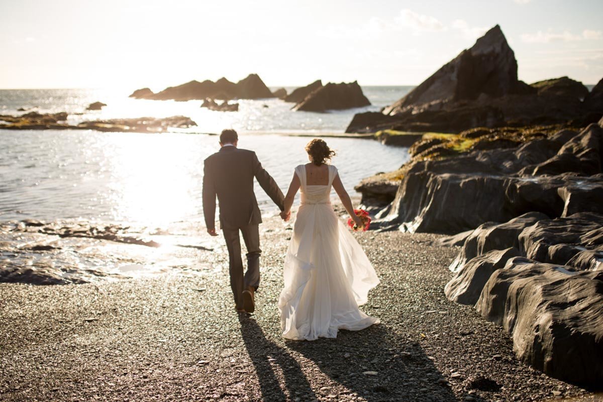 Couple on the beach walking towards the sea at their summer Tunnels Beaches Wedding