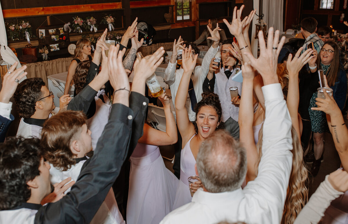 Group of people with their hands in the air dancing at wedding