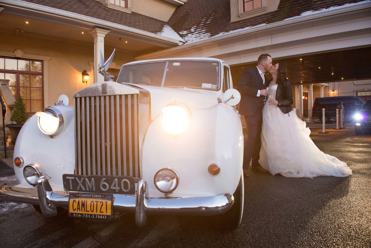 Bride and groom kissing by their vintage car at The Inn at New Hyde Park