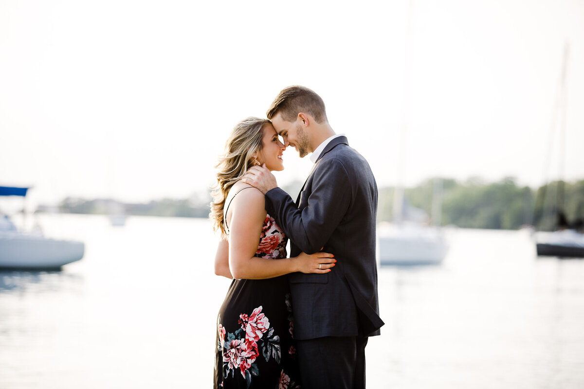 Engaged couple embracing in Buffalo Outer Harbour, New York with harbour boats in background