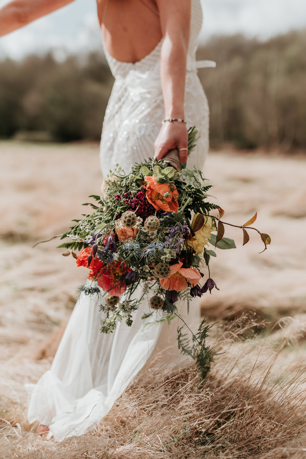 Wild, woodland wedding bouquet in a golden field at Two Woods Estate