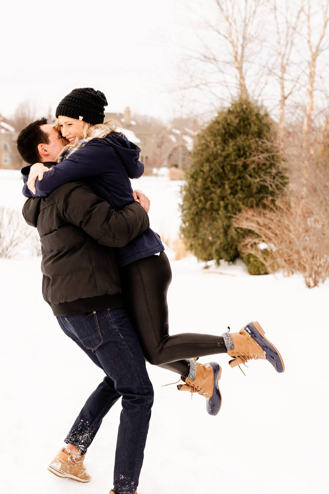 Man and woman playing in the snow during a fun anniversary photo session for couples near Chicago.