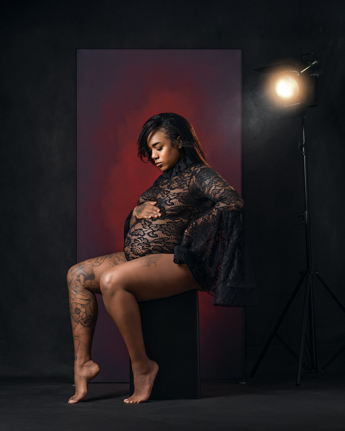 A cinematic fine art maternity portrait featuring dramatic lighting and black lace styling, photographed at AMM Fine Art Studio serving Seattle, Bellevue, Kirkland.