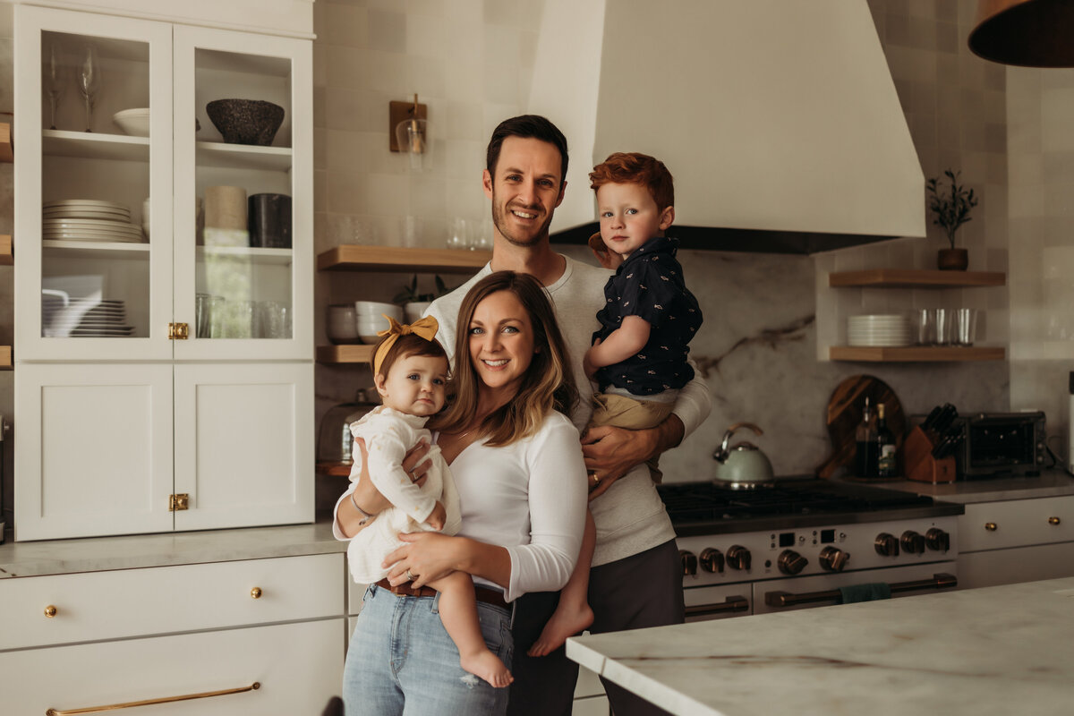 family of four stands together in designer kitchen