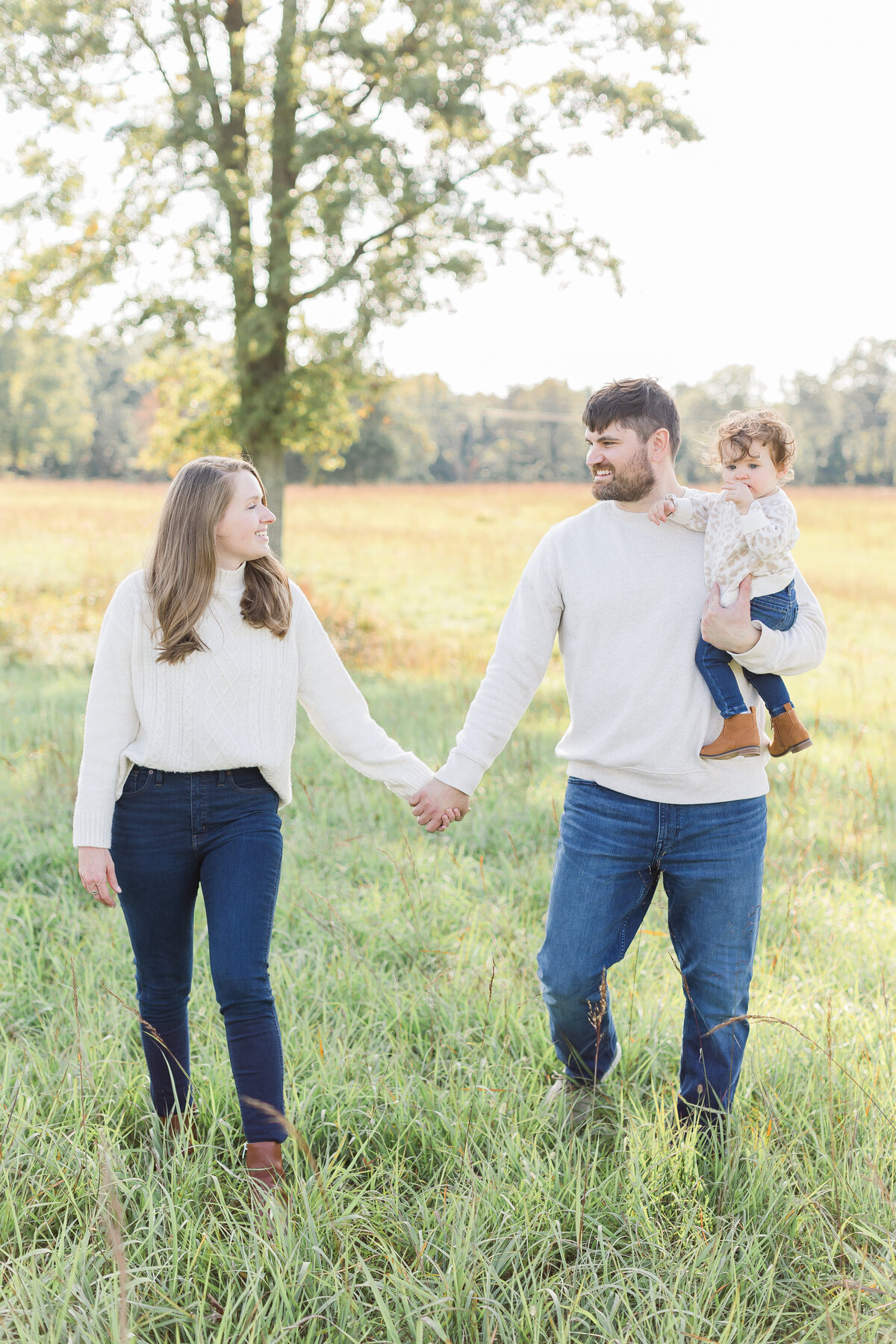 A family walking through tall green grass at sunset by Northern Virginia Family Photographer