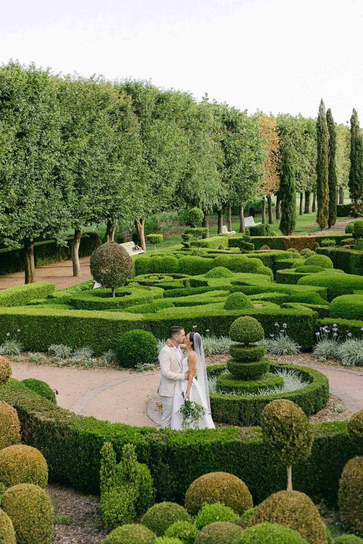 wedding couple's kiss surrounded by the maze in Merribee House Garden