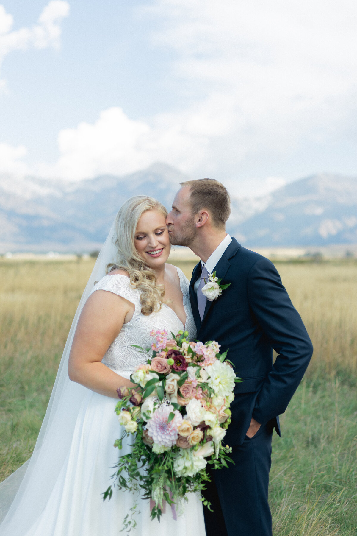 Groom kisses bride at mountain wedding