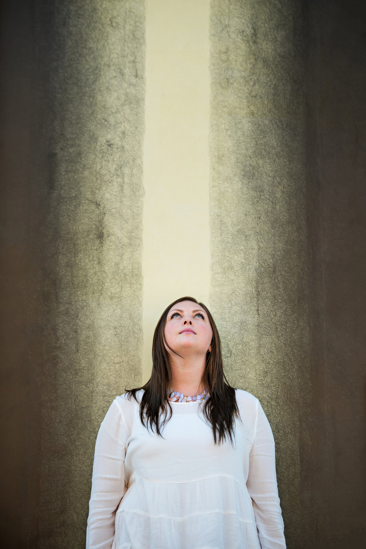 A woman in front of wall art looks up to the sky.