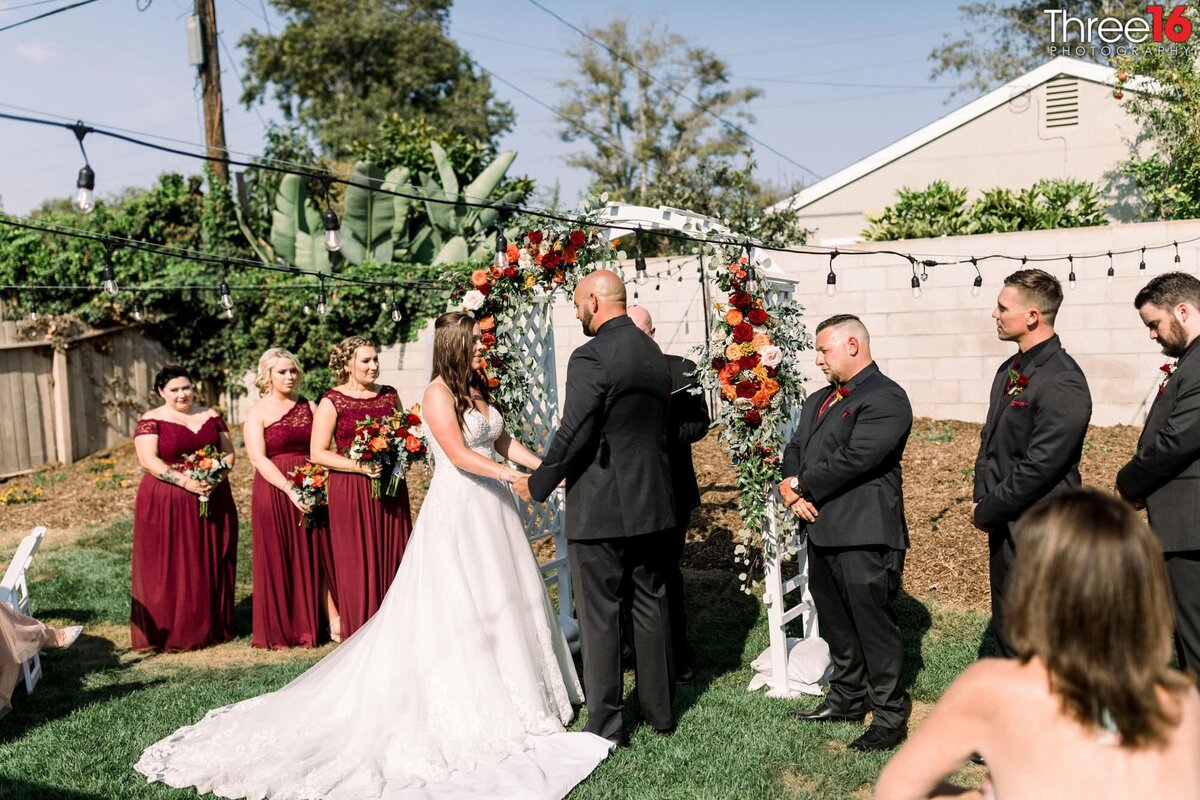 Bride and Groom hold hands during the ceremony in a backyard micro wedding