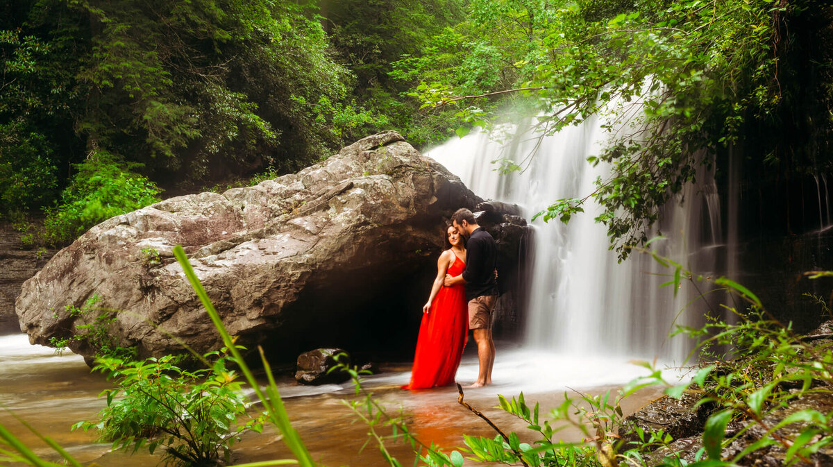 photo of a man and Woman hugging in front of a waterfall
