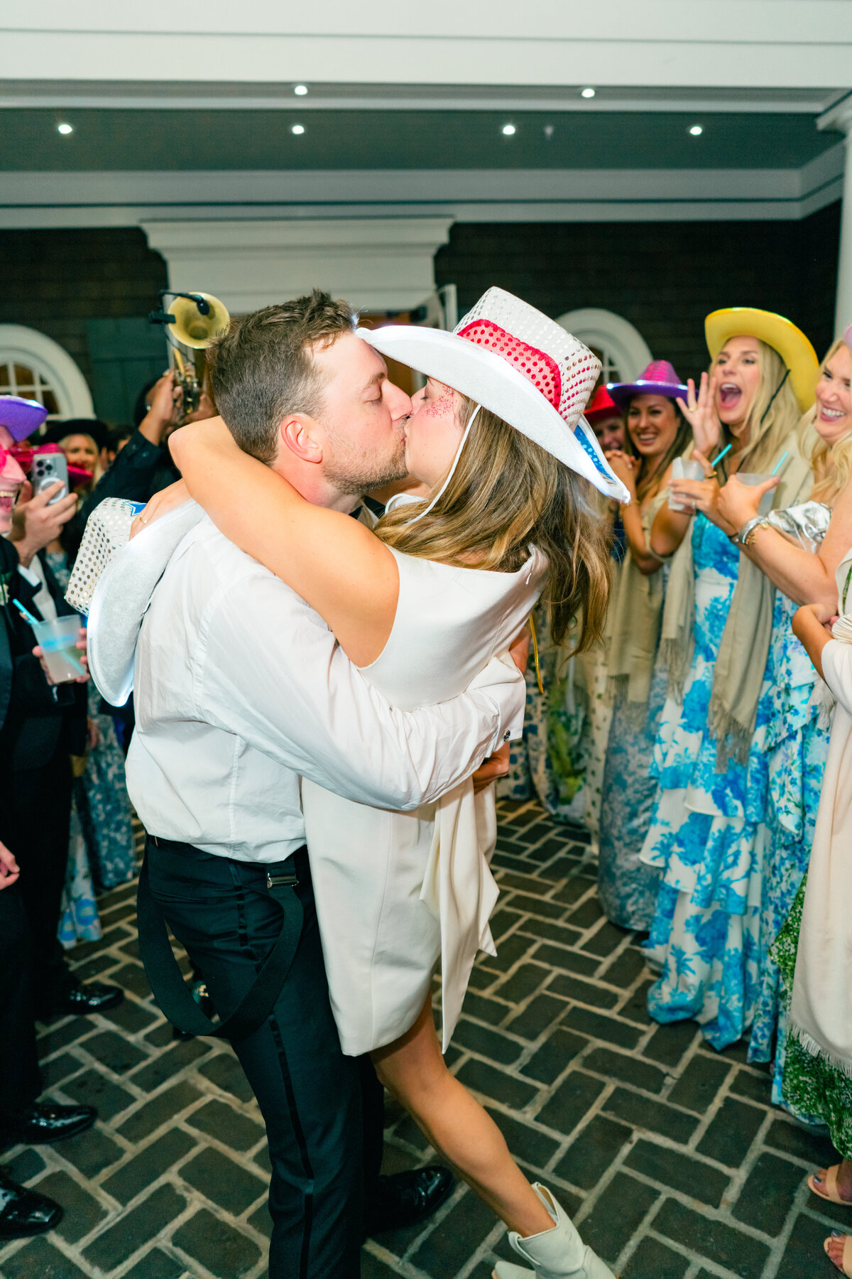 Bride and groom kiss before  jumping in the getaway car at Kiawah River Course wedding. Texas based couple brought out custom lone star cowboy hats for the perfect personal touch. Charleston wedding photographer.