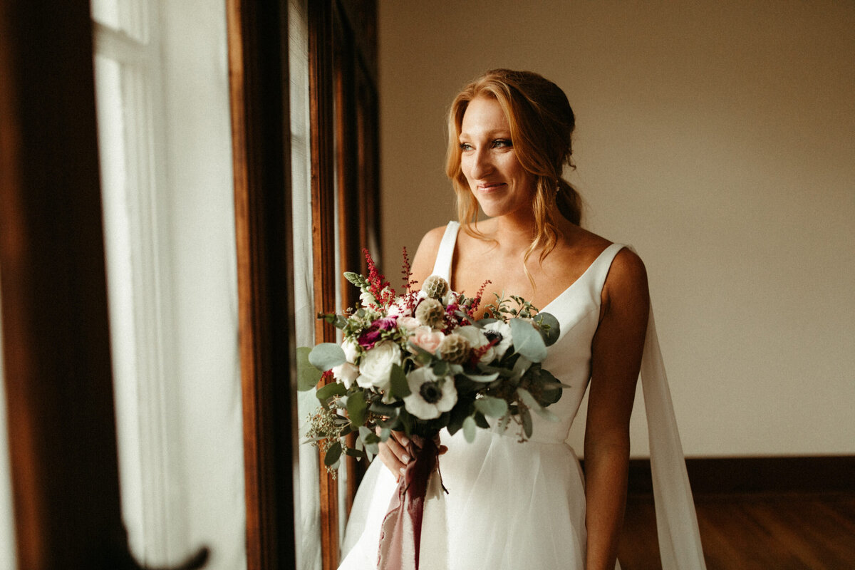Elegant bride with ponytail in wedding dress with shoulder capes