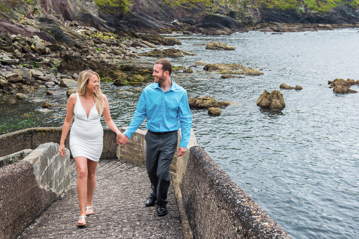 Engagement photograph of a man and woman  holding hands and walking on a pier