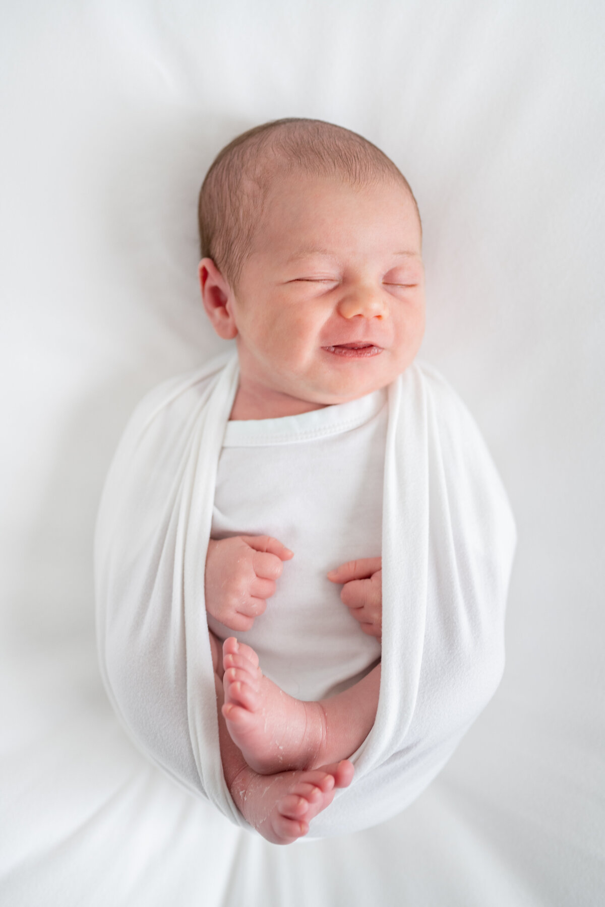 Newborn baby swaddled in a blanket with his feet sticking out