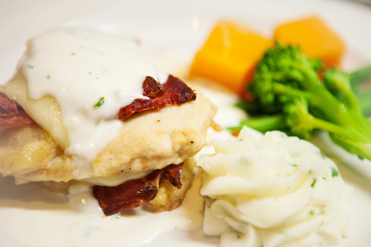 Chicken Cordon Bleu grilled chicken breast layered with provolone, dry-cured ham & topped with a garlic-crème sauce